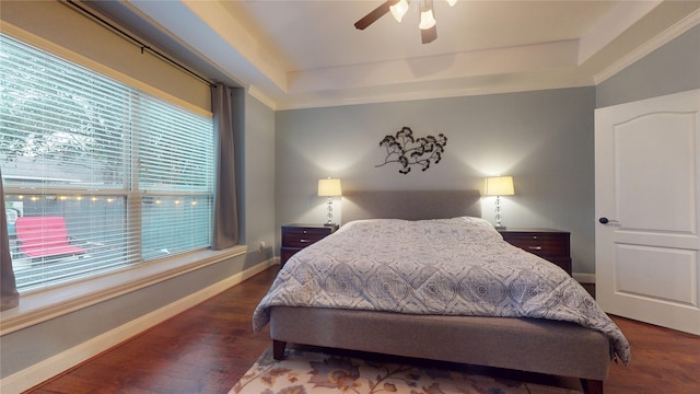 bedroom with ceiling fan, baseboards, a raised ceiling, and wood finished floors