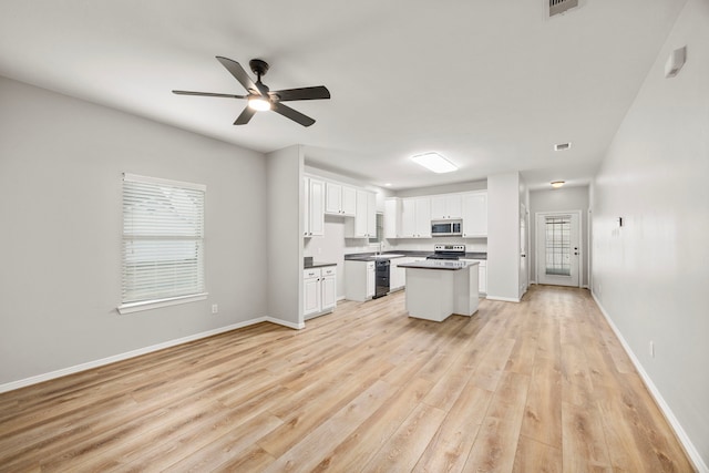 kitchen with light wood-type flooring, white cabinetry, appliances with stainless steel finishes, and baseboards