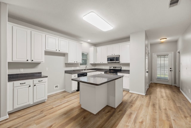 kitchen with a sink, visible vents, white cabinetry, appliances with stainless steel finishes, and dark countertops