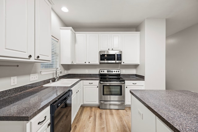 kitchen with dark countertops, white cabinetry, stainless steel appliances, and a sink