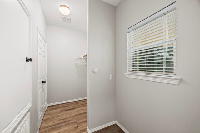 laundry area with wood finished floors, visible vents, and baseboards