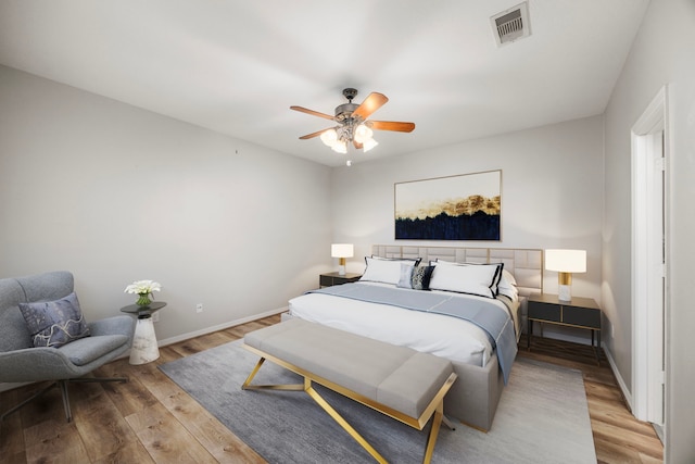 bedroom with ceiling fan, light wood-type flooring, visible vents, and baseboards