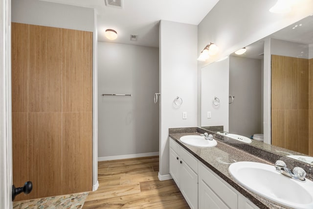 bathroom with double vanity, a sink, baseboards, and wood finished floors