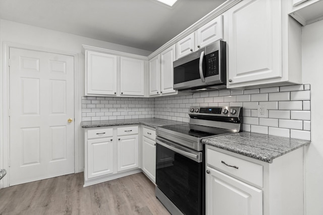 kitchen featuring appliances with stainless steel finishes, light wood-type flooring, white cabinetry, and decorative backsplash