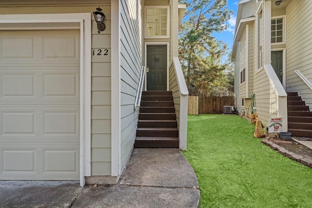 property entrance featuring central AC, fence, and a lawn