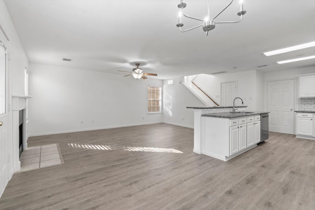 kitchen featuring white cabinets, a fireplace with flush hearth, light wood-style flooring, and a sink