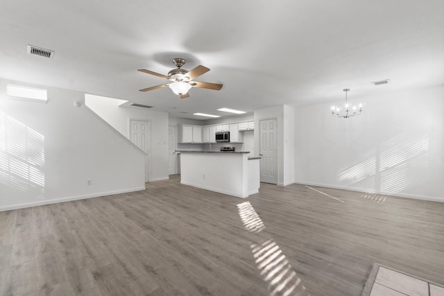 unfurnished living room with ceiling fan with notable chandelier, light wood finished floors, and visible vents