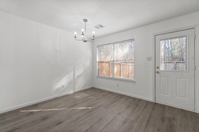 unfurnished dining area with baseboards, wood finished floors, visible vents, and an inviting chandelier