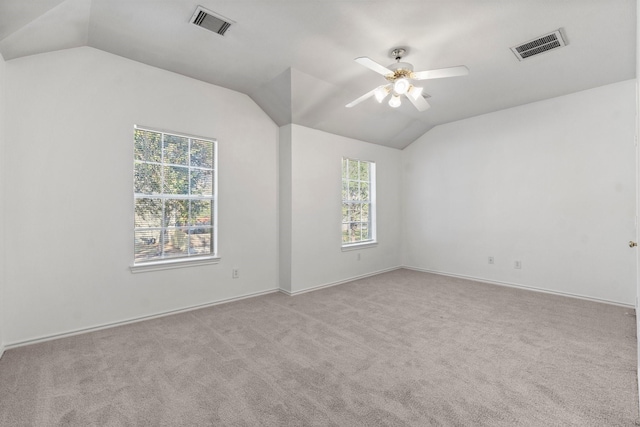 carpeted spare room with vaulted ceiling, visible vents, and a ceiling fan