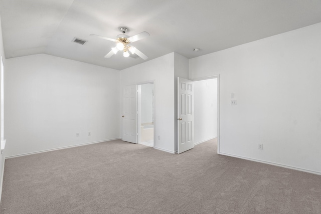 unfurnished bedroom featuring visible vents, a ceiling fan, ensuite bathroom, carpet, and vaulted ceiling