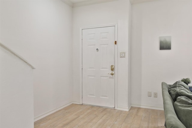 entryway featuring ornamental molding, light wood-type flooring, and baseboards