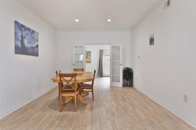 dining space featuring light wood-type flooring, visible vents, french doors, and crown molding
