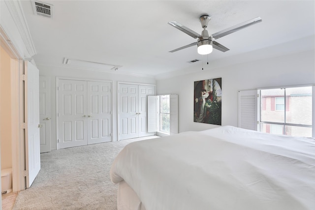 bedroom featuring carpet floors, visible vents, ornamental molding, and two closets