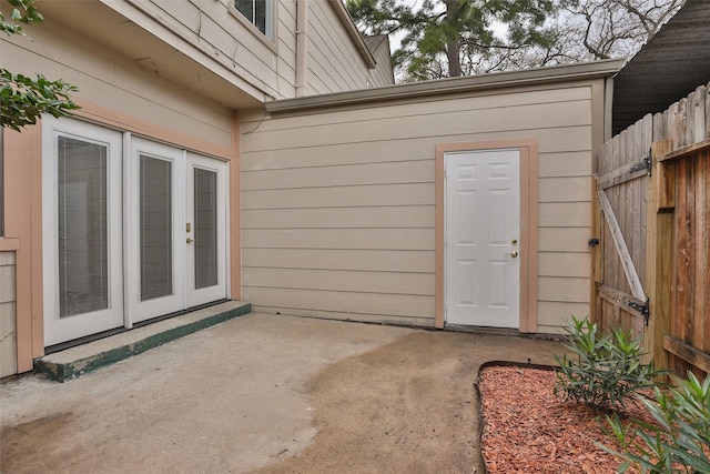 view of exterior entry featuring french doors, a patio, and fence