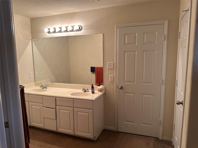 bathroom featuring a sink, a textured ceiling, double vanity, and a textured wall