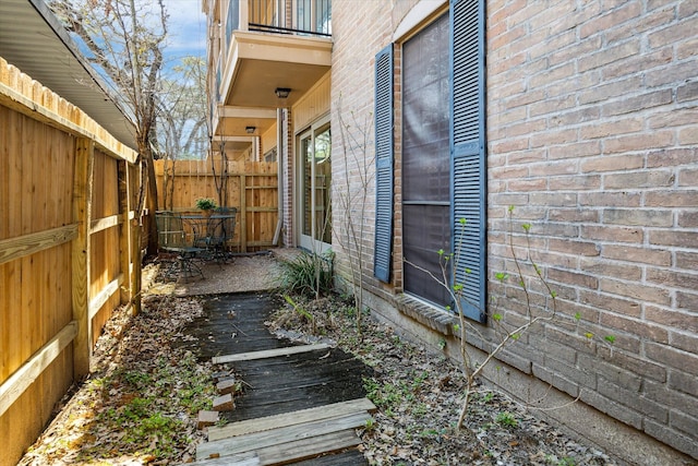 view of side of property featuring brick siding, fence, and a wooden deck