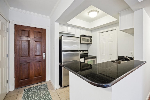 kitchen featuring dark countertops, appliances with stainless steel finishes, a peninsula, white cabinetry, and a sink