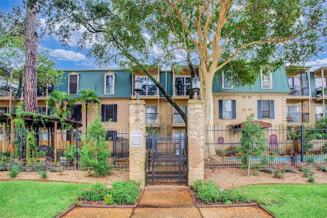 multi unit property with brick siding, a fenced front yard, and a gate