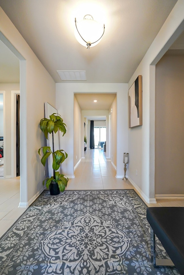 hallway featuring tile patterned flooring, visible vents, and baseboards