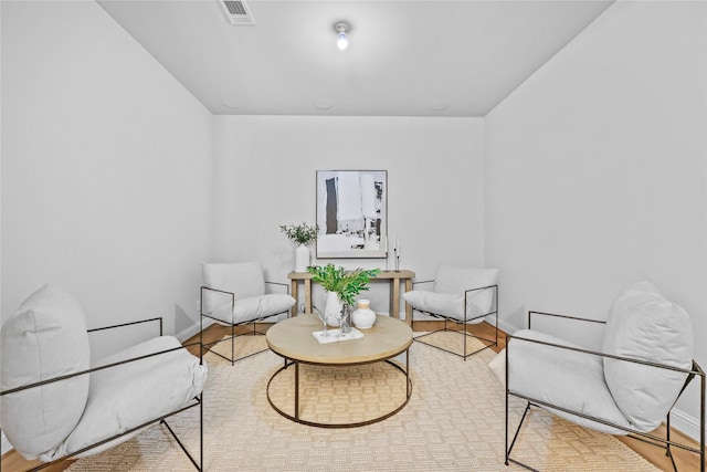 living area featuring visible vents, baseboards, and wood finished floors