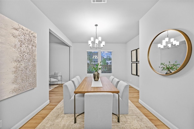 dining room with light wood-style flooring, visible vents, a chandelier, and baseboards