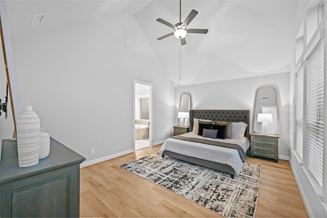 bedroom with high vaulted ceiling, connected bathroom, light wood-style flooring, and baseboards