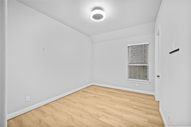 unfurnished bedroom featuring baseboards, lofted ceiling, and light wood-style floors