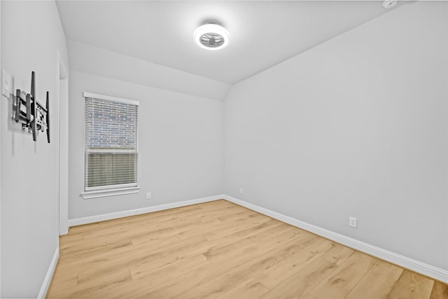 empty room featuring vaulted ceiling, baseboards, and wood finished floors