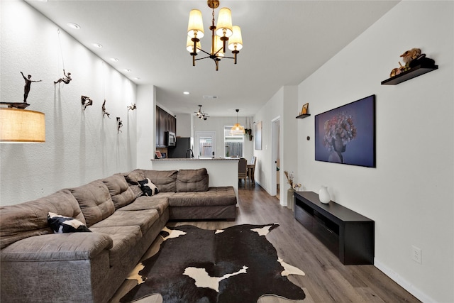 living room with recessed lighting, baseboards, an inviting chandelier, and wood finished floors