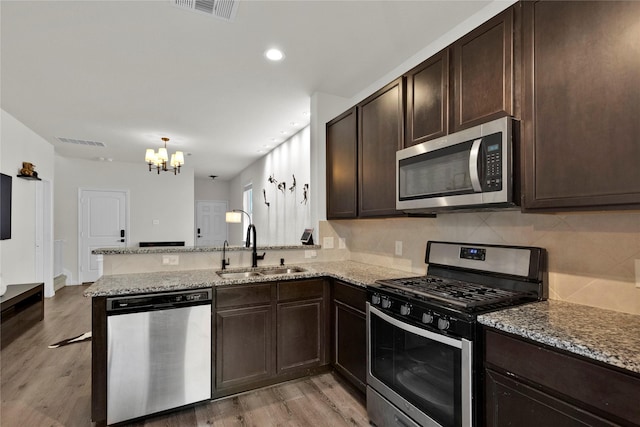 kitchen featuring dark brown cabinetry, visible vents, appliances with stainless steel finishes, and a sink