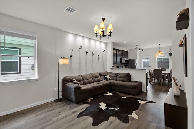 living area featuring baseboards, visible vents, wood finished floors, a chandelier, and recessed lighting