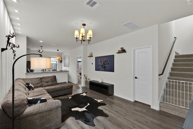 living room with stairway, wood finished floors, visible vents, and a notable chandelier