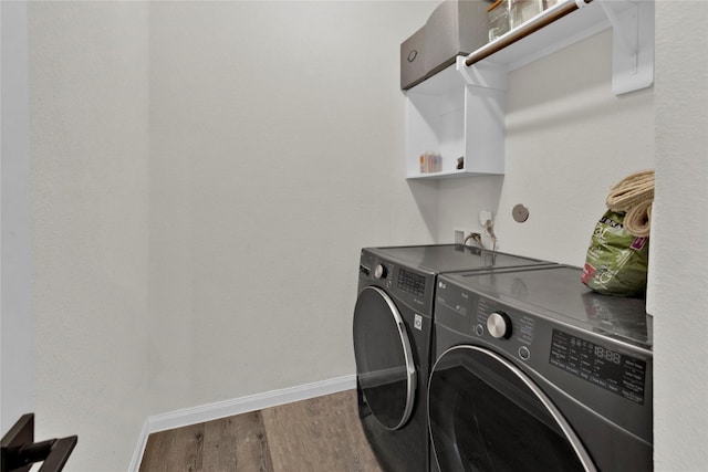 laundry room with laundry area, wood finished floors, washing machine and dryer, and baseboards