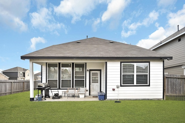 back of house with a shingled roof, a fenced backyard, a yard, and a patio