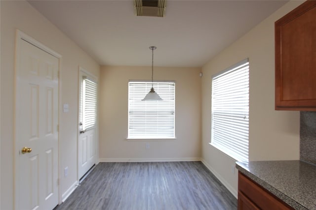 unfurnished dining area featuring dark wood-style flooring, visible vents, and baseboards