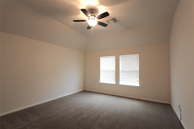 spare room with a ceiling fan, visible vents, vaulted ceiling, baseboards, and dark carpet