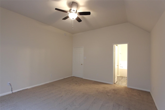 carpeted spare room with a ceiling fan, vaulted ceiling, and baseboards