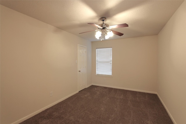 spare room featuring a ceiling fan, dark carpet, a textured ceiling, and baseboards