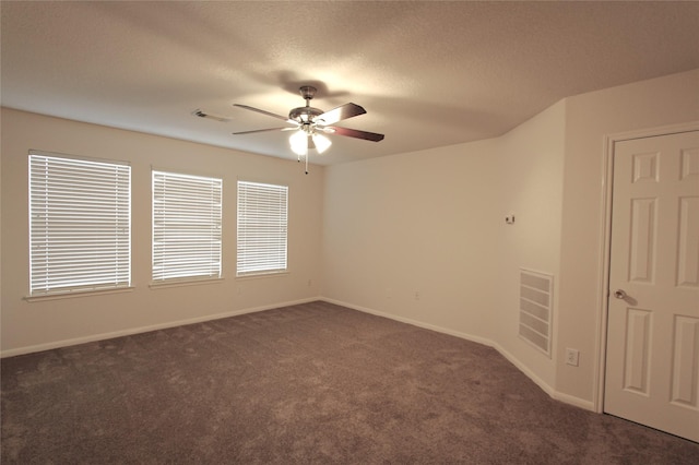 carpeted empty room featuring a ceiling fan, visible vents, a textured ceiling, and baseboards