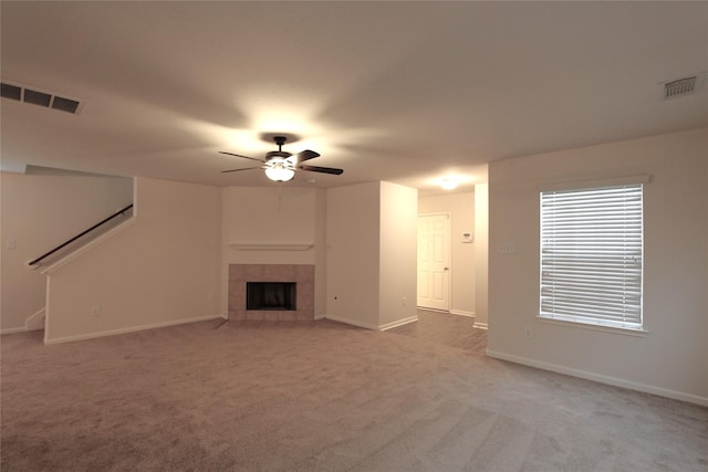 unfurnished living room with light carpet, stairway, a tiled fireplace, and visible vents