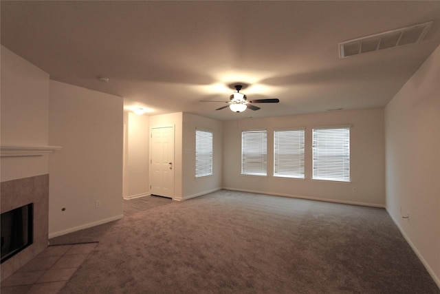 unfurnished living room featuring a tile fireplace, baseboards, visible vents, and carpet flooring