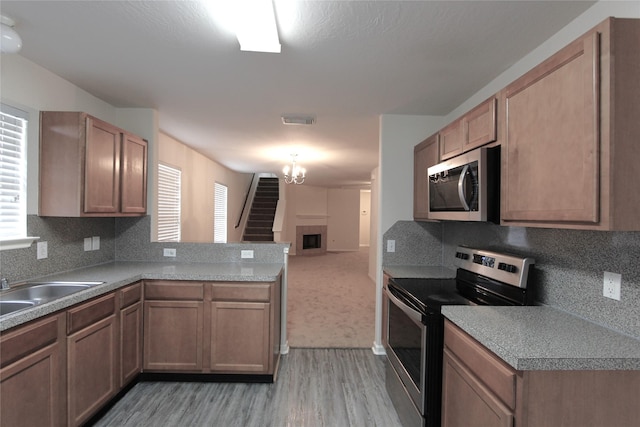 kitchen with a peninsula, a fireplace, visible vents, open floor plan, and appliances with stainless steel finishes