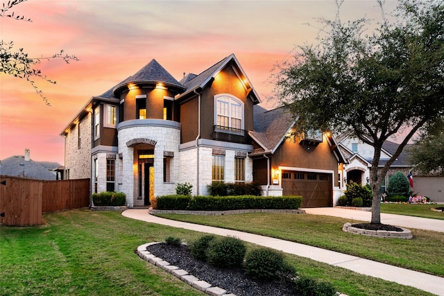 french provincial home with stone siding, fence, concrete driveway, and a front yard