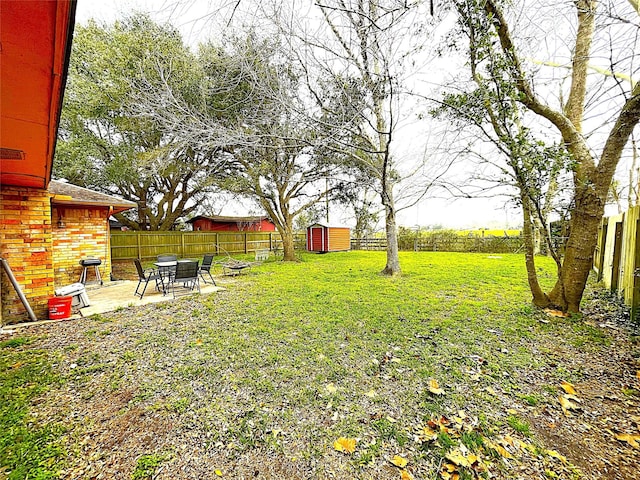 view of yard featuring a patio area, a shed, a fenced backyard, and an outbuilding