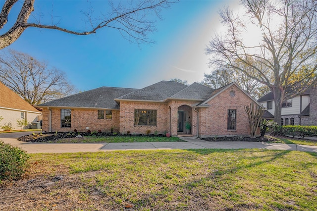 view of front of home featuring brick siding, concrete driveway, a shingled roof, and a front yard