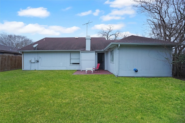 back of property featuring a patio, fence, roof with shingles, a lawn, and a chimney