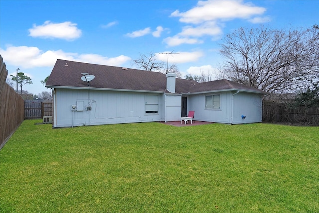 rear view of property featuring a patio area, a fenced backyard, a chimney, and a lawn