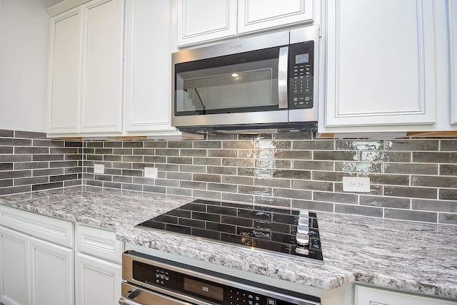 kitchen featuring wall oven, decorative backsplash, white cabinets, stainless steel microwave, and black electric cooktop