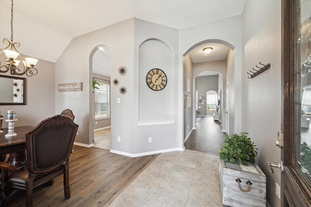 interior space featuring a chandelier, arched walkways, baseboards, and wood finished floors