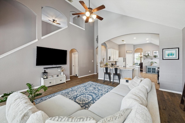 living room with arched walkways, wood finished floors, and a ceiling fan